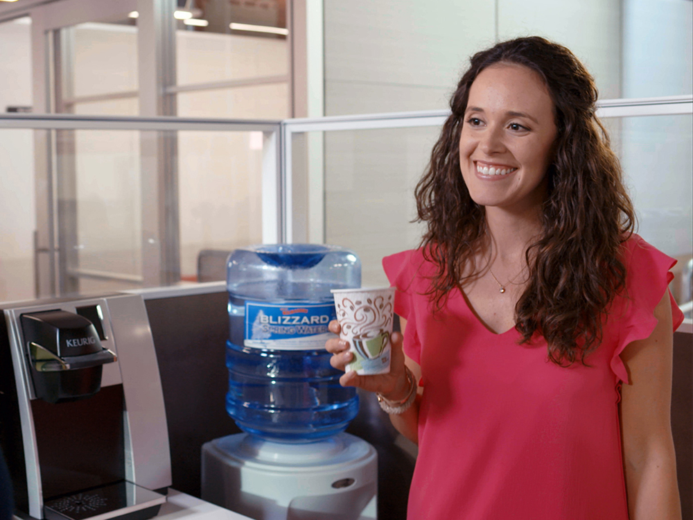 Woman standing by water cooler with a cup of water
