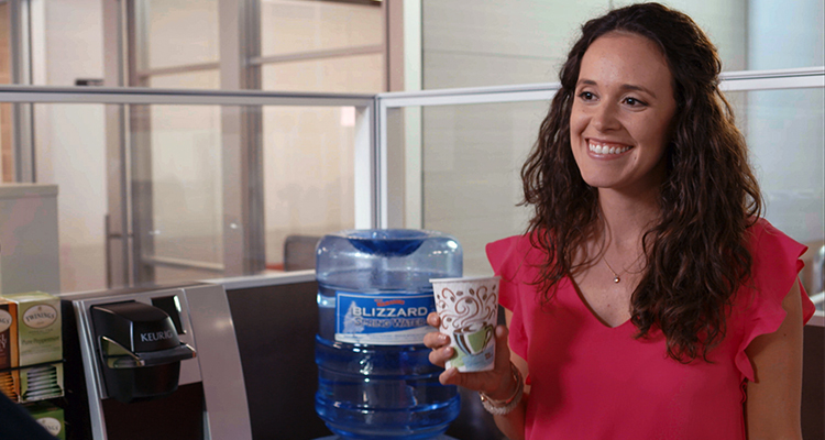 Woman with cup of water near a water cooler